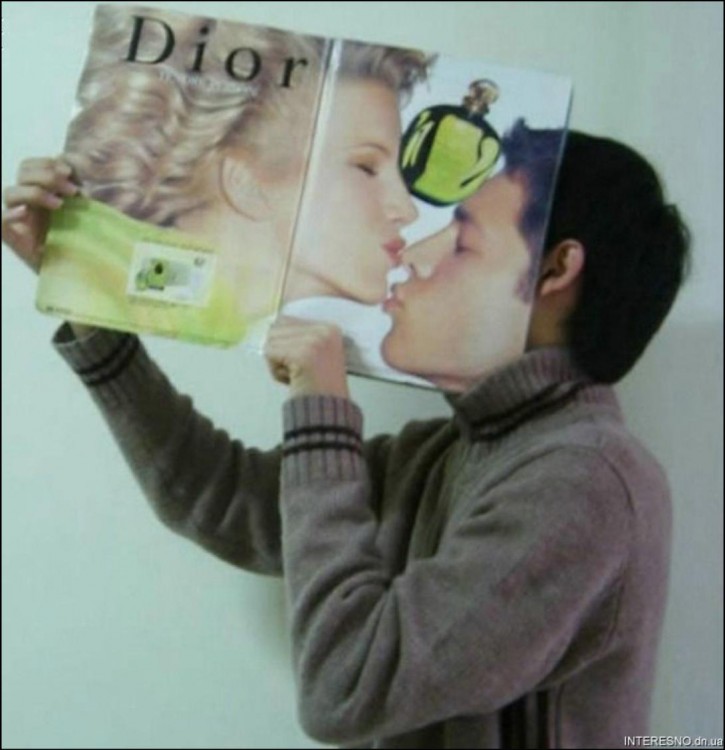 un chico con una revista frente a su cara que parece estar besando a una modelo de revista 