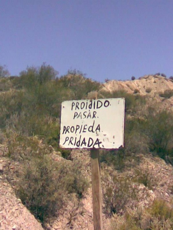 Letrero sostenido con un palo en un lugar fuera de la ciudad que prohíbe el paso 