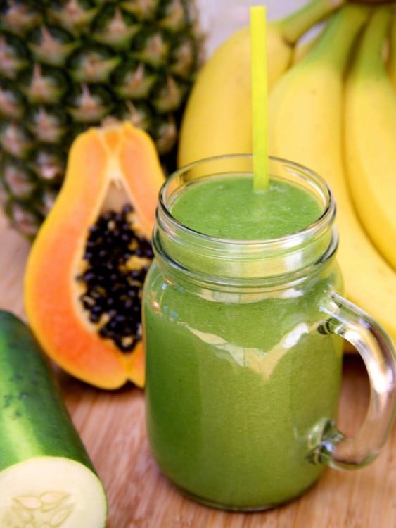 Licuado de papaya dentro de un vaso rodeado de algunas frutas 