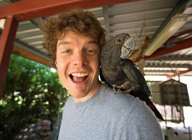 selfie de un chico con un ave parada en su hombro 