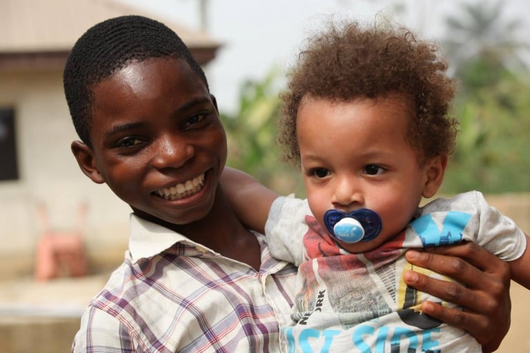 Hope en brazos de joven nigeriano sonriendo