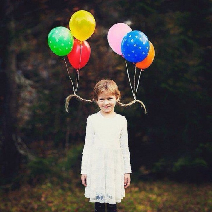 niña con dos trenzas y globos atados a ellas 