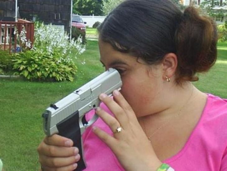mujer apuntando a su ojo con una pistola