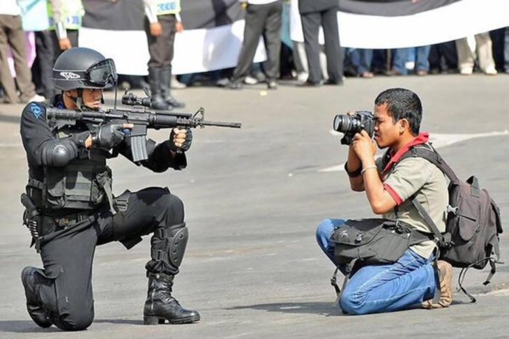 policía apuntando a un fotógrafo