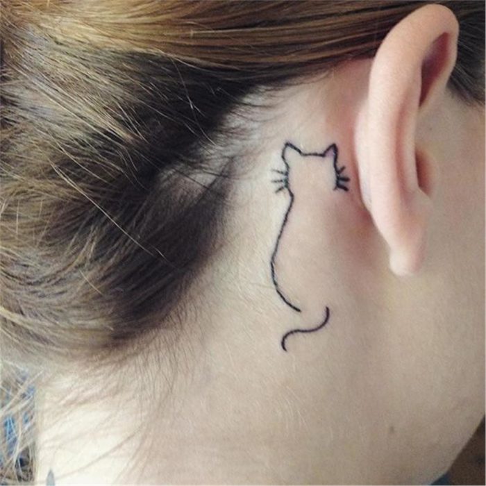 Tatuaje minimalista de gato en la parte de atrás de la oreja