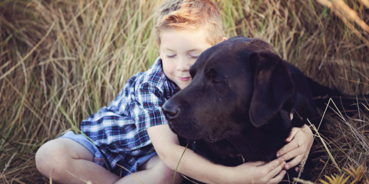 niño abrazando perrito negro